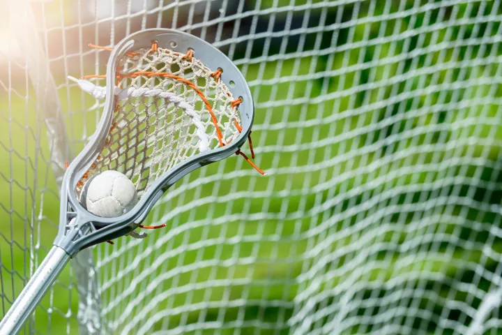 Lacrosse stick scooping up a ball in front of the net