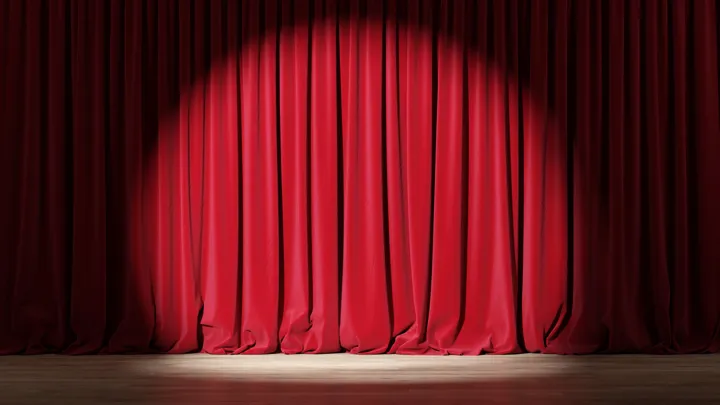Spotlight on closed red curtains on a stage