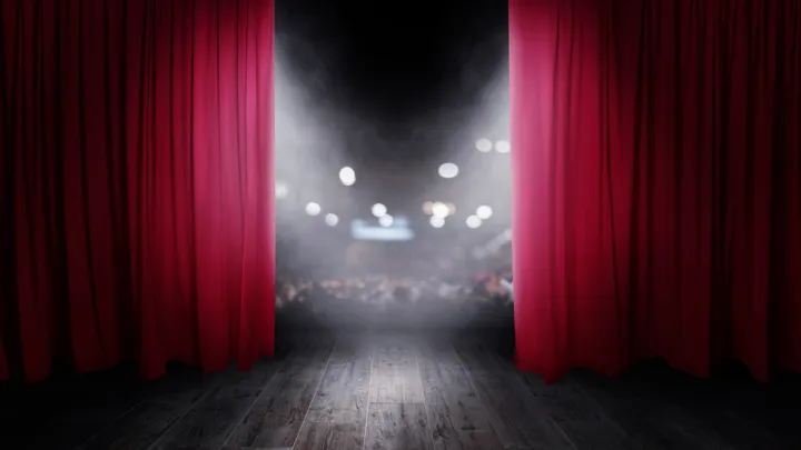 Curtains on a stage opening to a theater